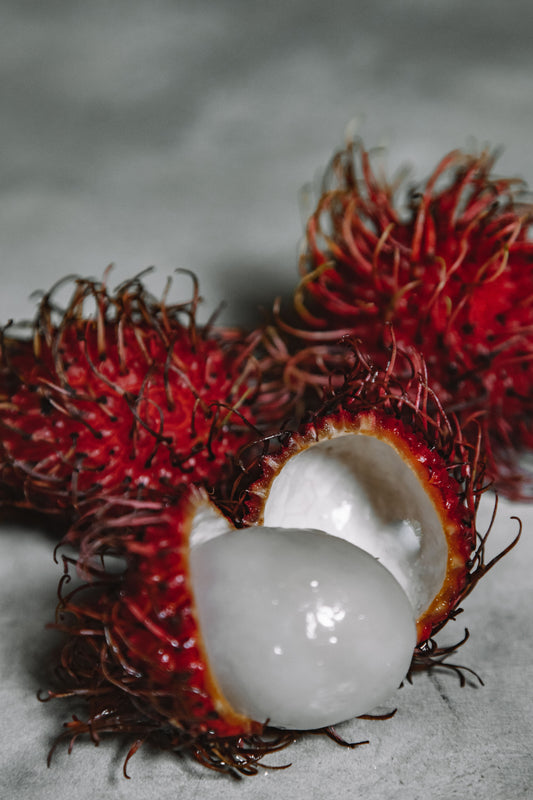 Fresh rambutan with one peeled showing white flesh